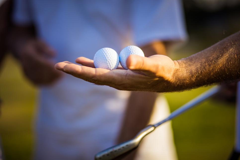 A person holding two golf balls in hand