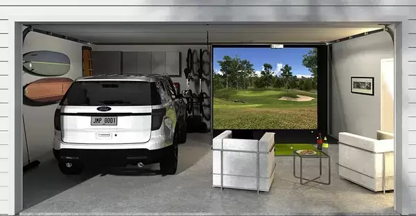A view of a garage gold simulator with a monitor and car parked at one side