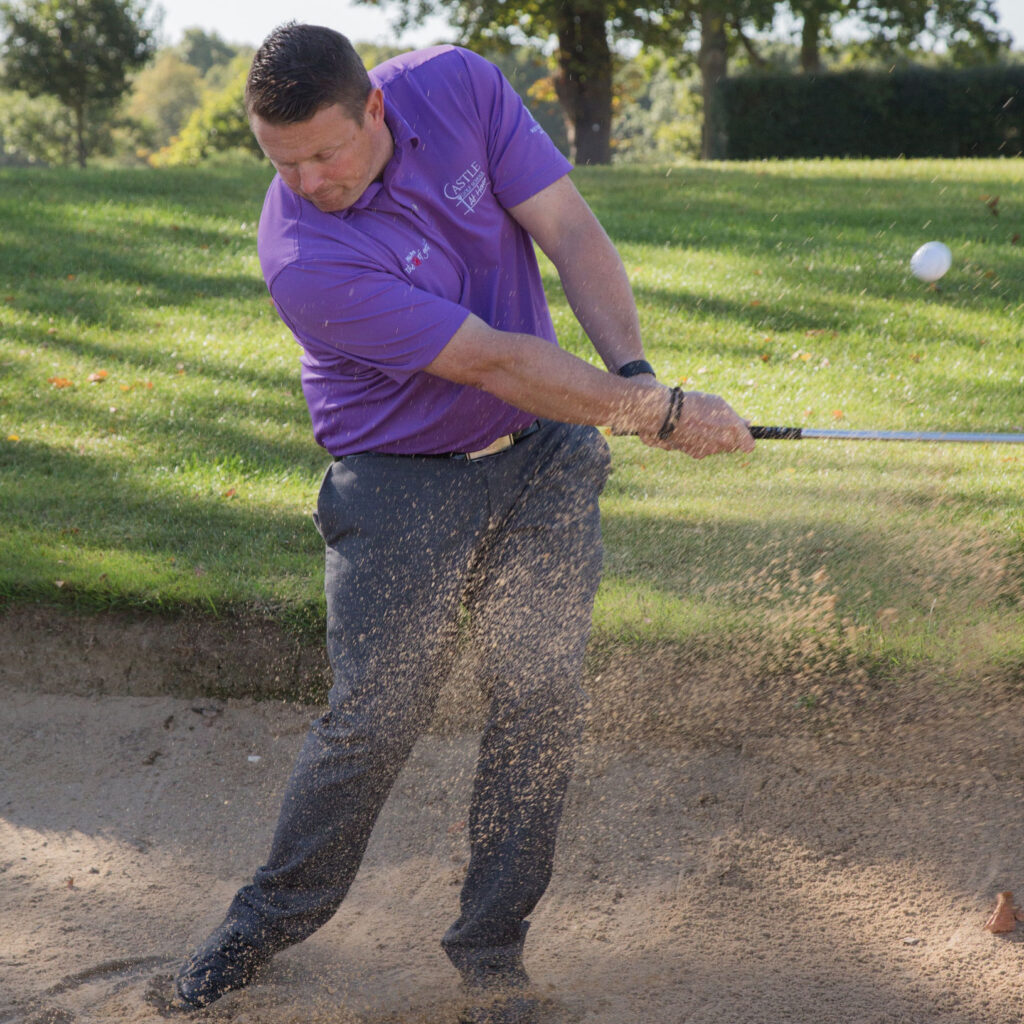 A view of person hitting the golf ball and dirt flying in the air
