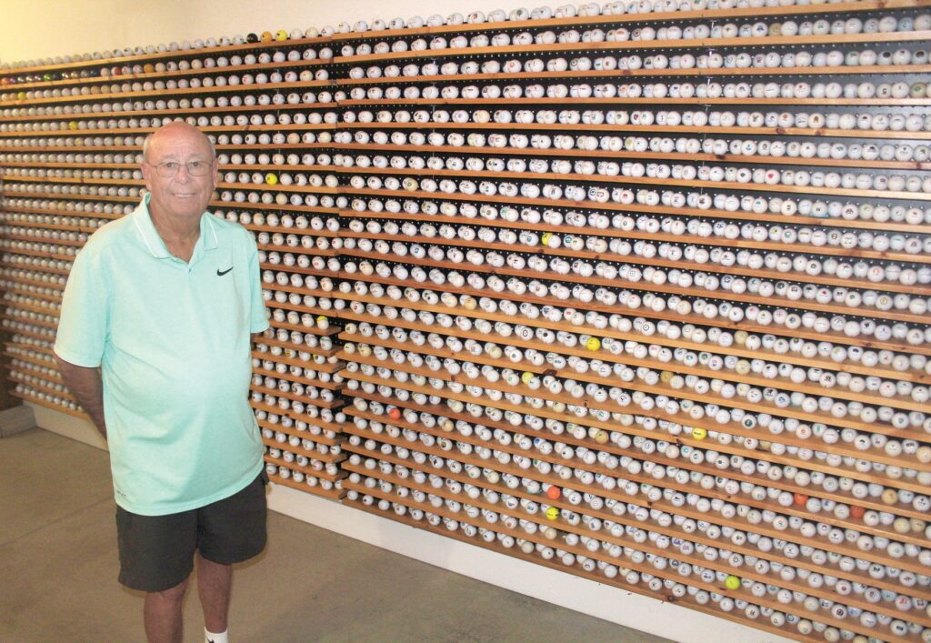 An old man standing next to a golf ball collection in garage