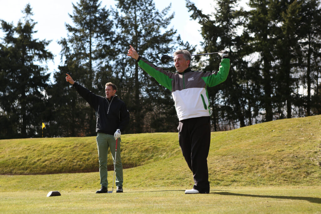 Two people raising a hand after hitting the hole at a golf course
