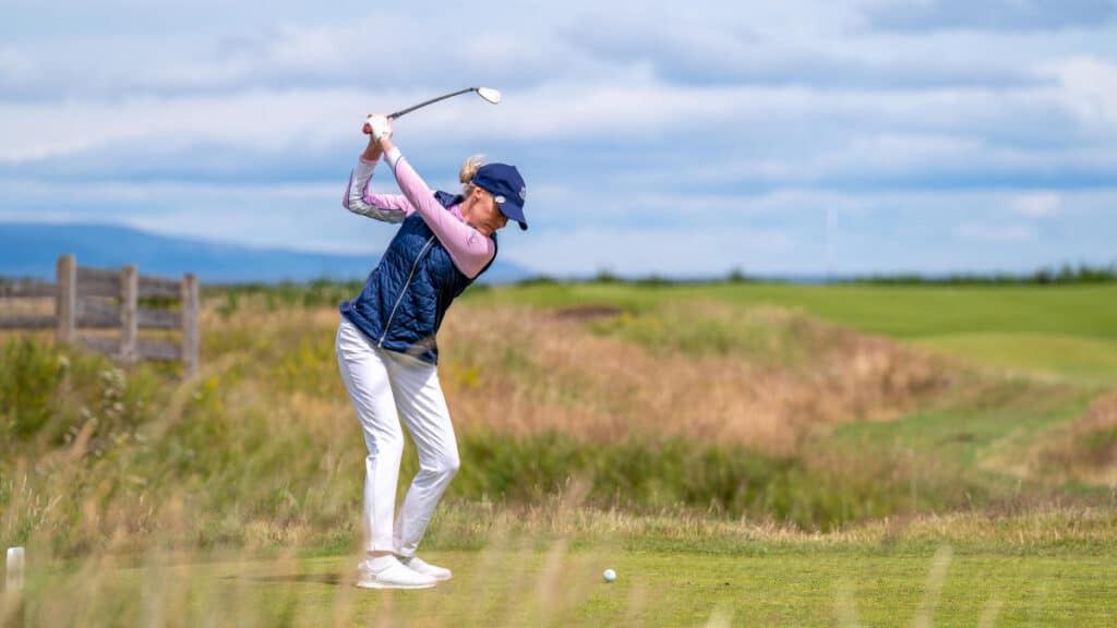 A girl hitting the golf ball on a grass golf field