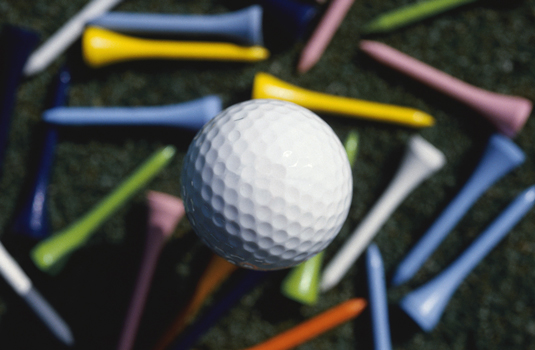 A golf ball in centre with colorful tees surrounding