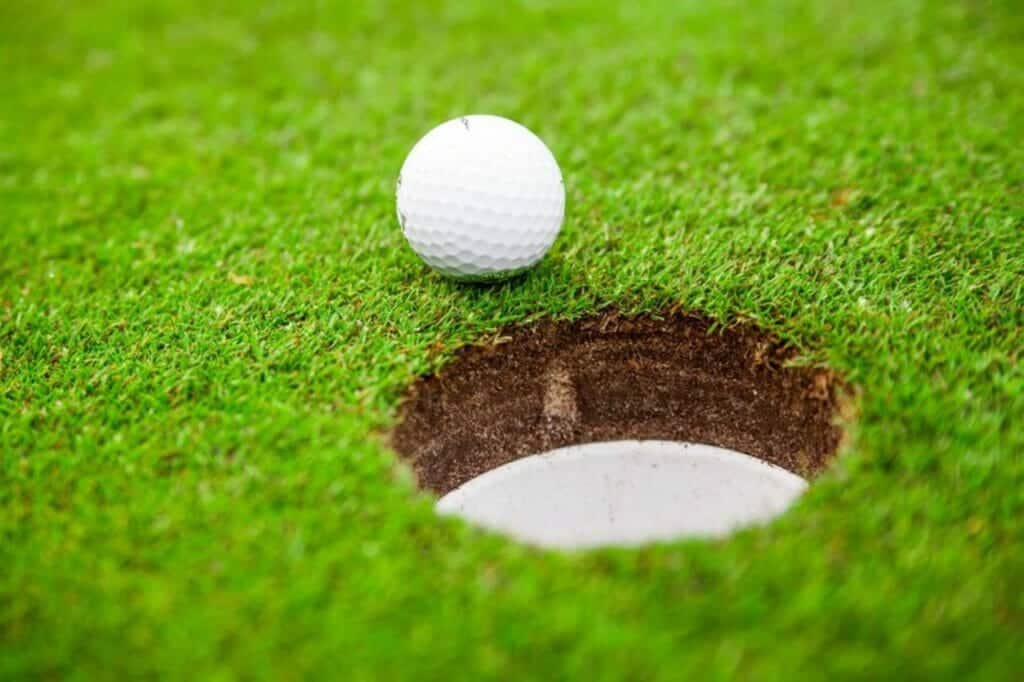 A golf ball near a scoring hole on golf course