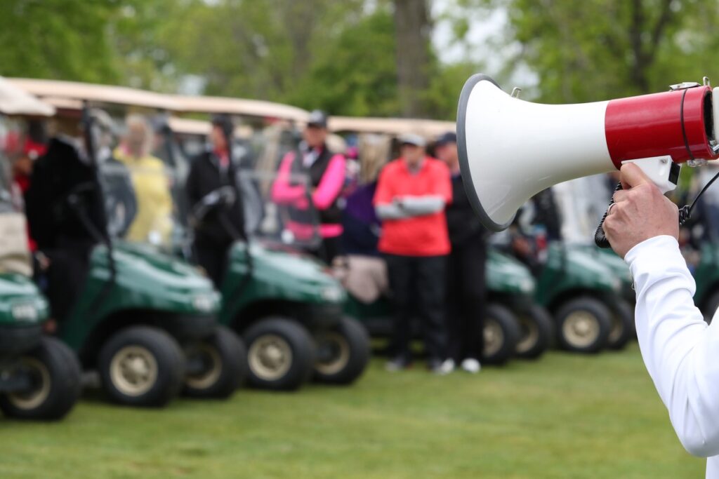 A person holding a speaker announcing the start of shotgun golf