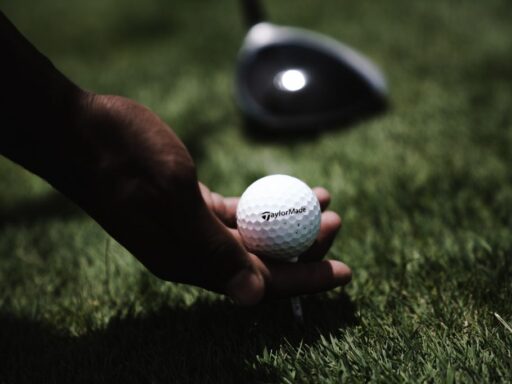 A person holding the golf ball from the grass measuring its diameter