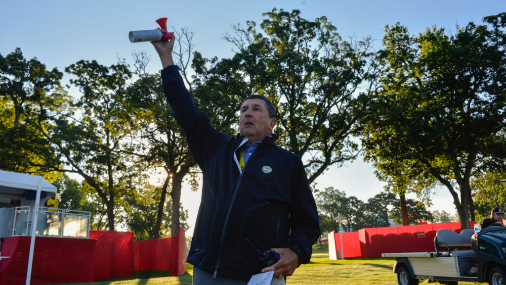A person holding the horn in air at a shotgun start golf event