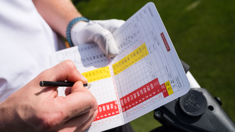 A person marking the golf scorecard
