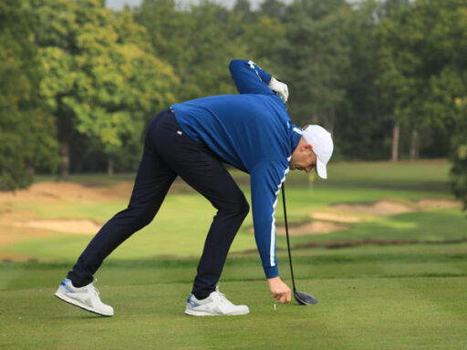 A person placing a golf ball bending over getting ready for a provisional golf shot
