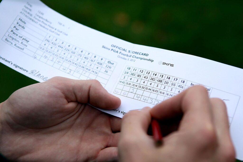 A person writing score on a golf scorecard