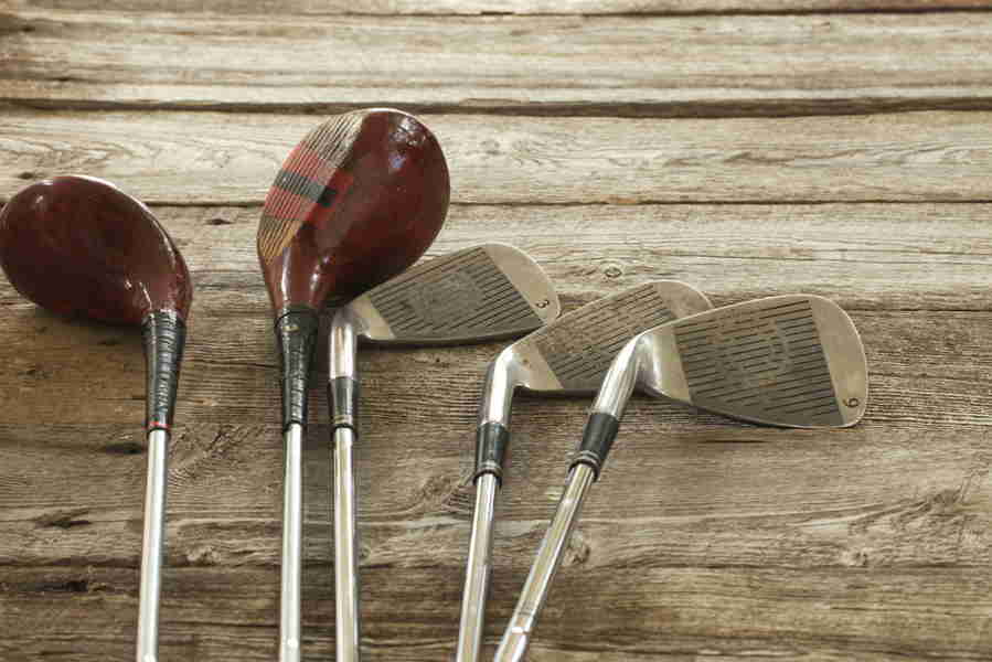 A top view of old golf clubs on a wooden table