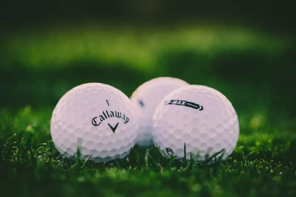 Three Callaway golf balls on green grass