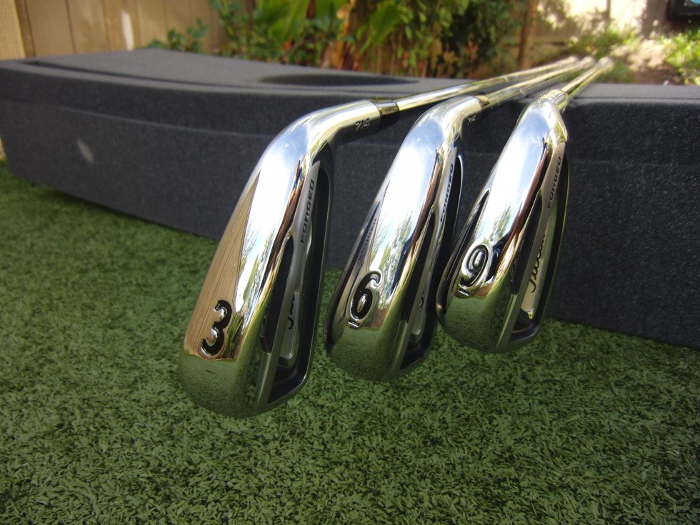 Three shiny silver golf clubs placed on a board