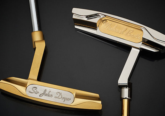 Two gold plated golf clubs resting in opposite directions