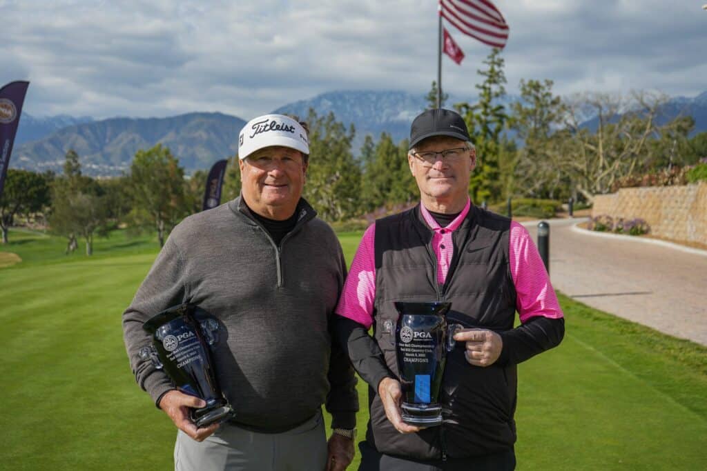 Two golfers holding a PGA golf ball champions trophy