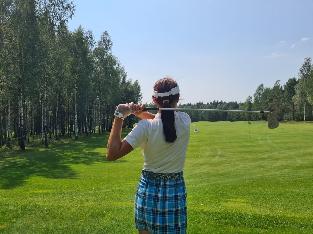 A back shot of a lady holding a golf club