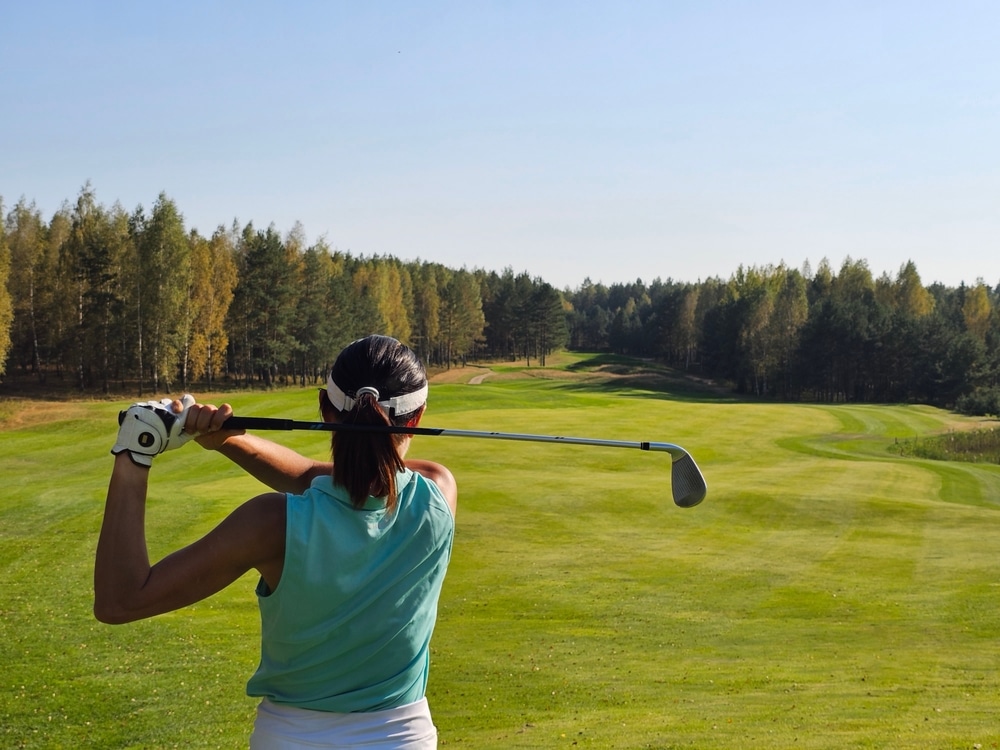 A back view of a woman hitting golf club shot