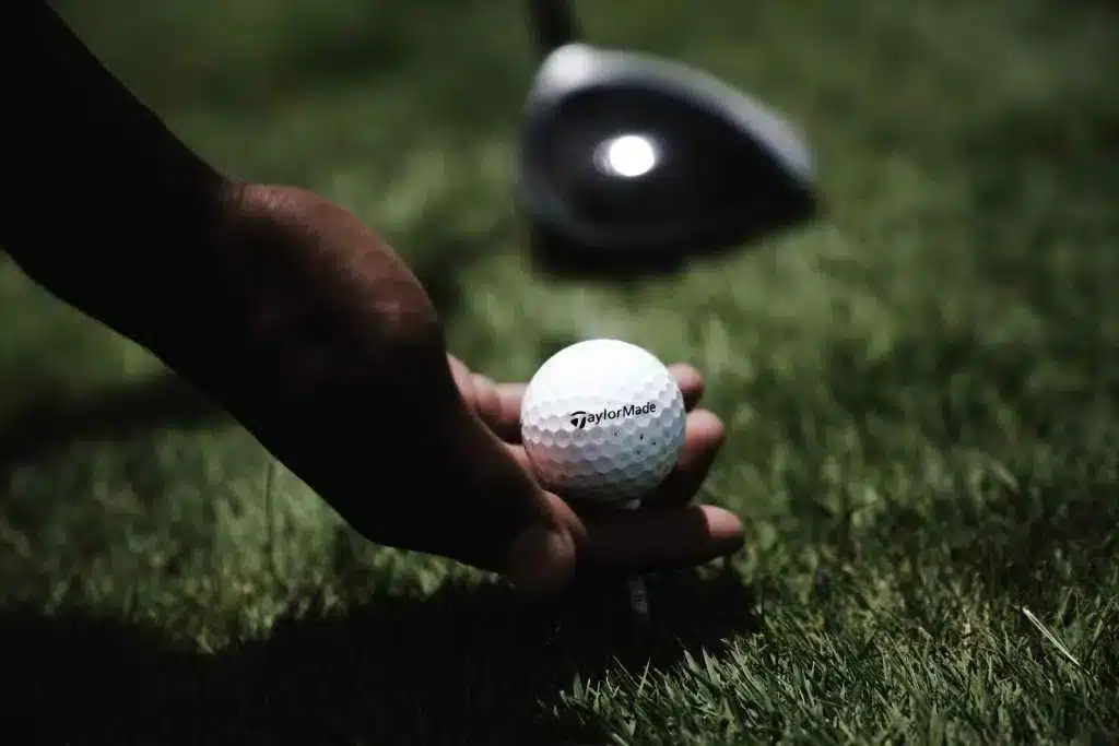 A person holding the golf ball from the grass measuring its diameter