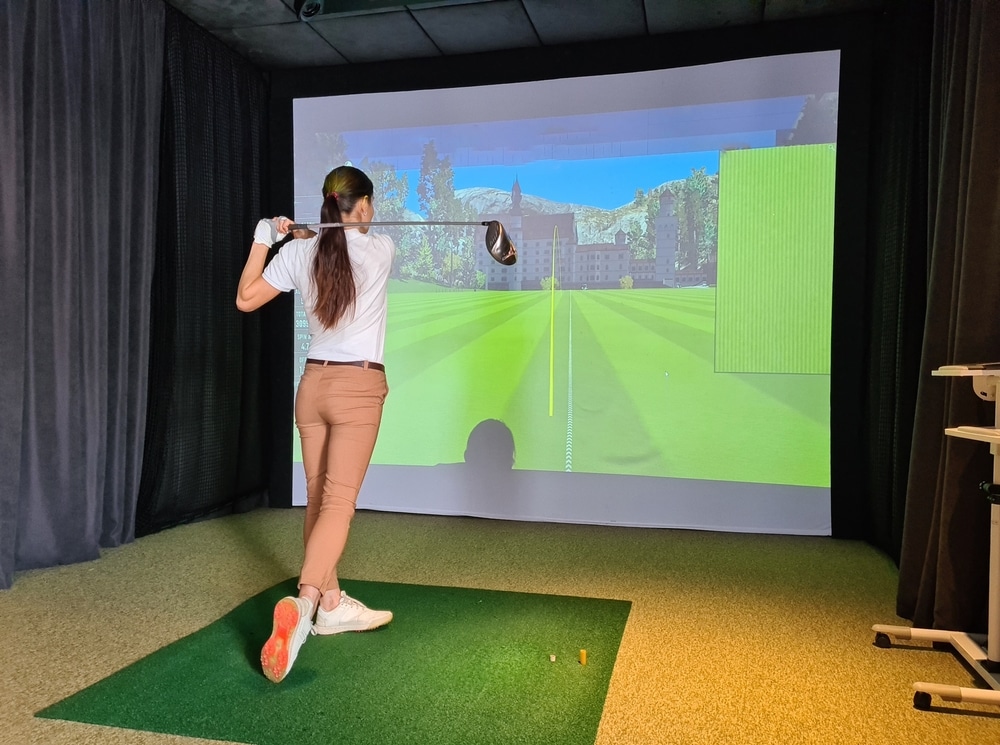 A view of a girl playing golf on a simulator