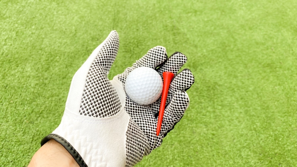 A view of a person wearing gloves holding a golf ball