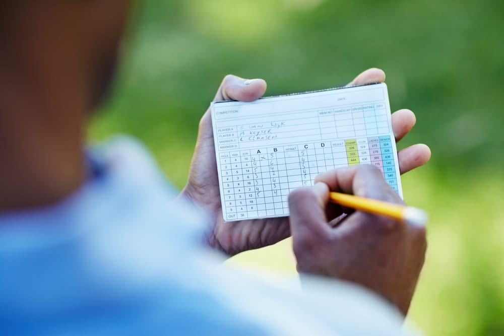 A view of a person writing score on a golf card