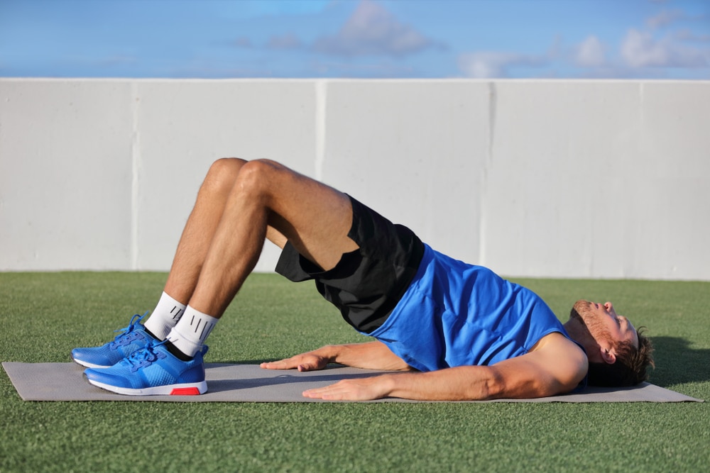 Fitness man doing bodyweight glute floor bridge pose