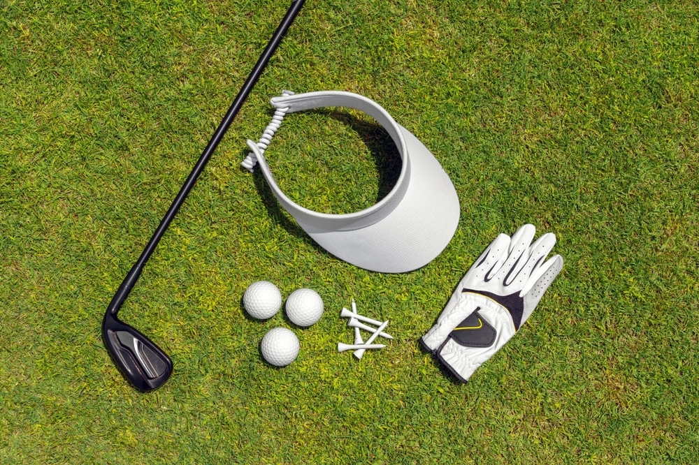 Flat lay of golf club, balls, glove, tees and cap