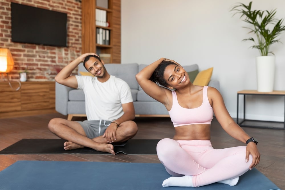 Smiling young black guy and lady in sportswear doing exercises