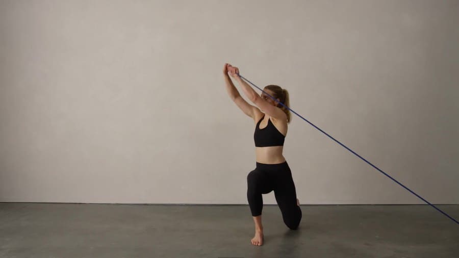 a female exercising core rotation holding a rope in a room