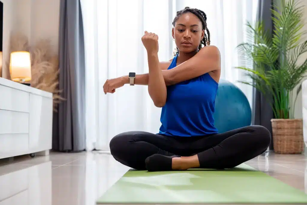 a girl doing shoulder stretches sitting on a mat