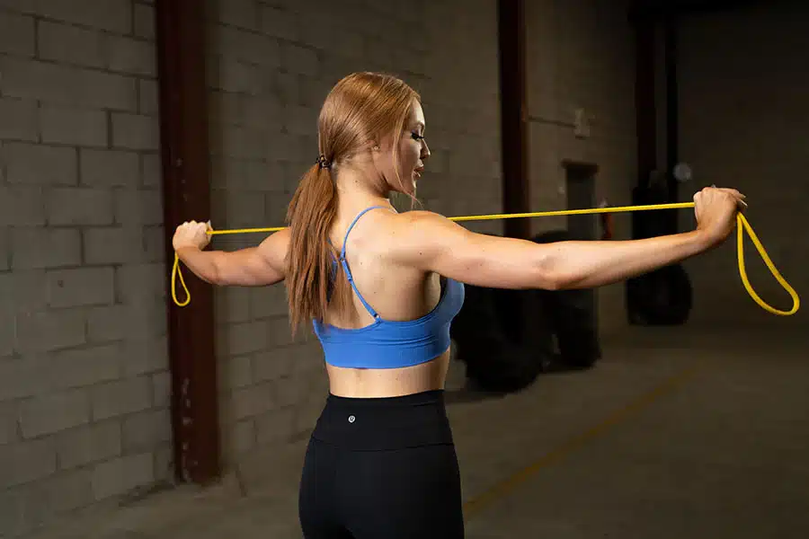 a girl holding a string and doing rotator cuff exercise