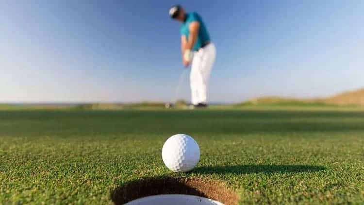 a golf ball near a hole in a ground