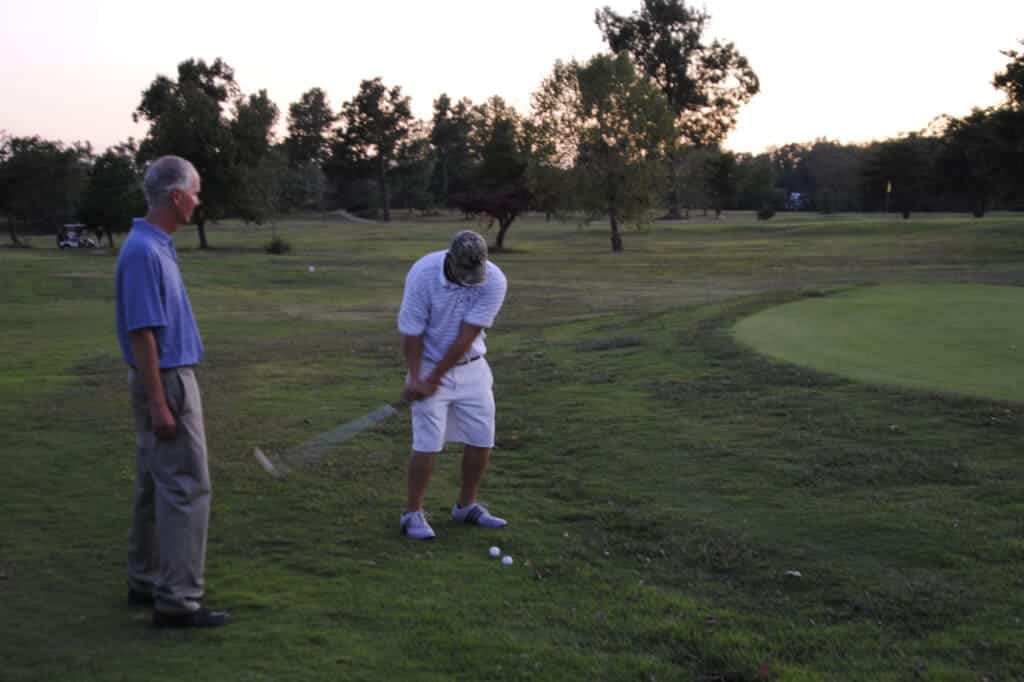 a malke playing golf other one observing in the ground