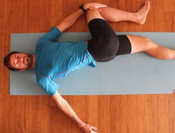 a person stretching his legs lysing on a mat