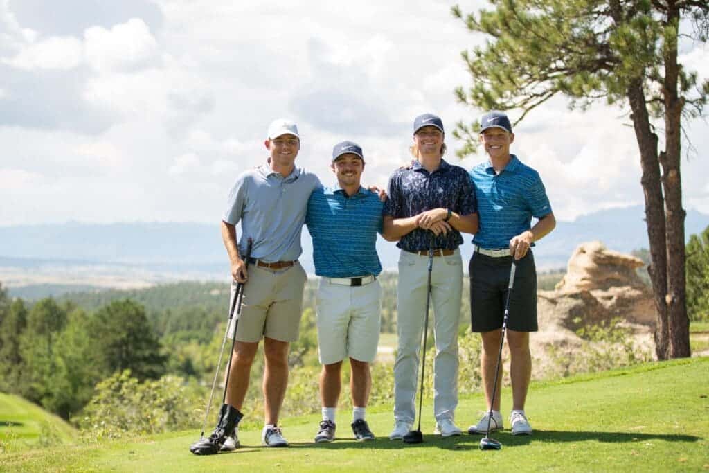 boys playing posing for a picture in a ground of them holding clubs