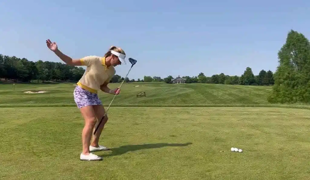 female golfer holding a golf club and standing in a ground balls placed on the ground