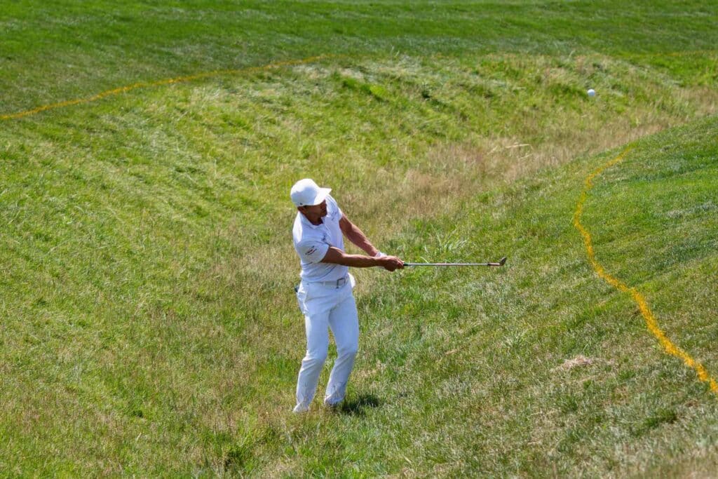 golfer holding a club standing in a field