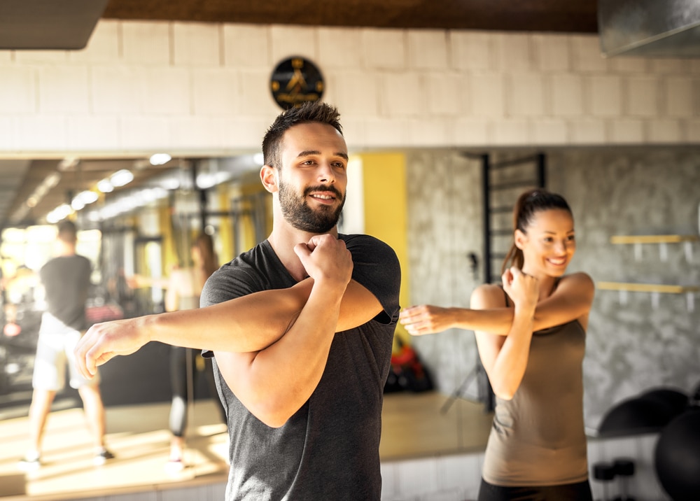 male and female atheletes doing shoulder stretches