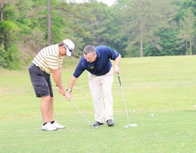 trainer giving lessons to a person to play golf