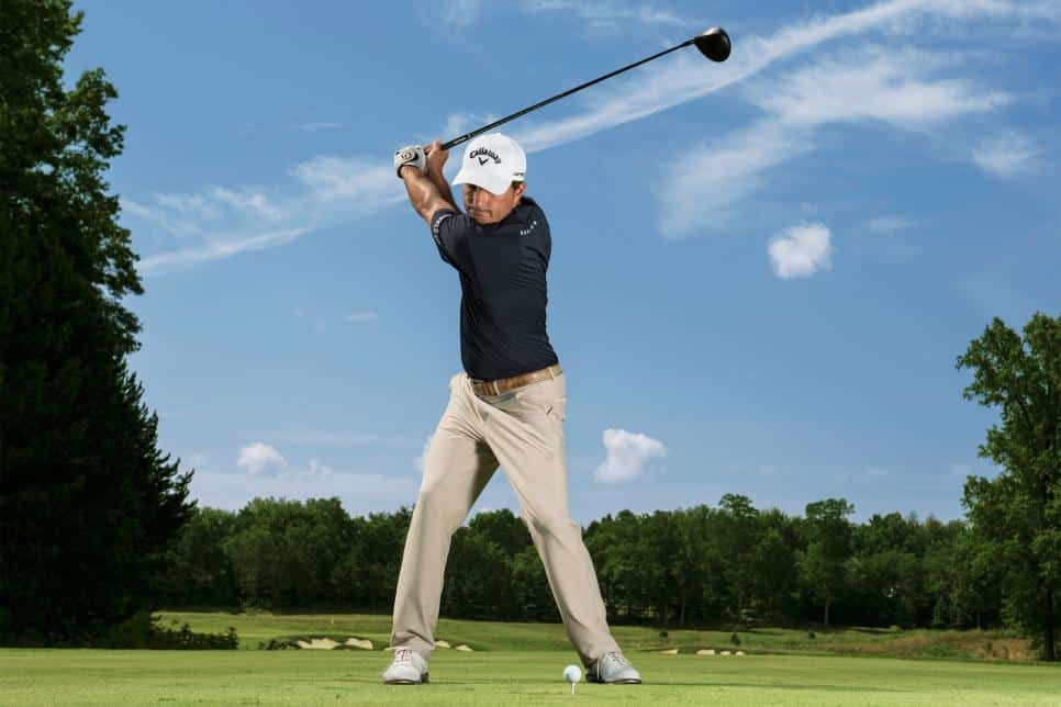 zoomed in view of golfer standing in ground about to hit the ball with club