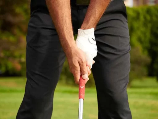 zoomed in view of golfer's hands, one with glove, holding a club in a ground