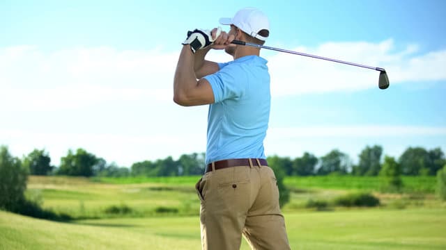 Male golfer with golf club on field looking away