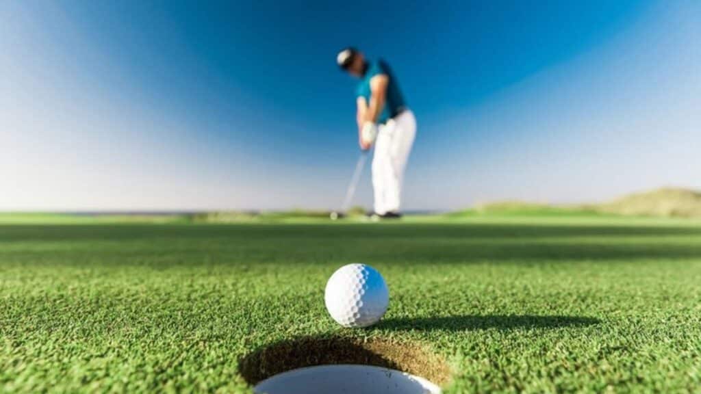 a golfer is putting a golf ball in a hole