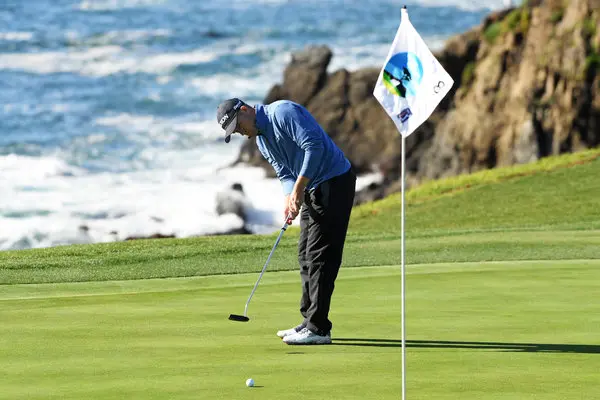 a golfer is putting a golf ball in a hole