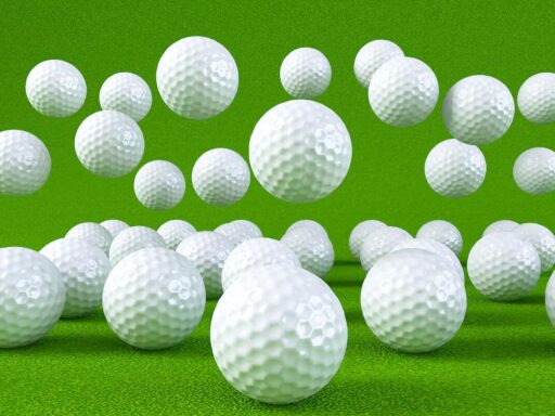 alot of golf balls on a grass carpet