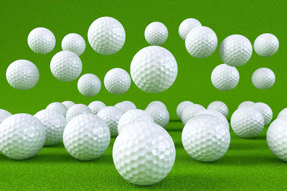 alot of golf balls on a grass carpet