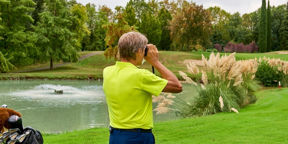 The Golfer Accurately Measures The Distance To The Flag In