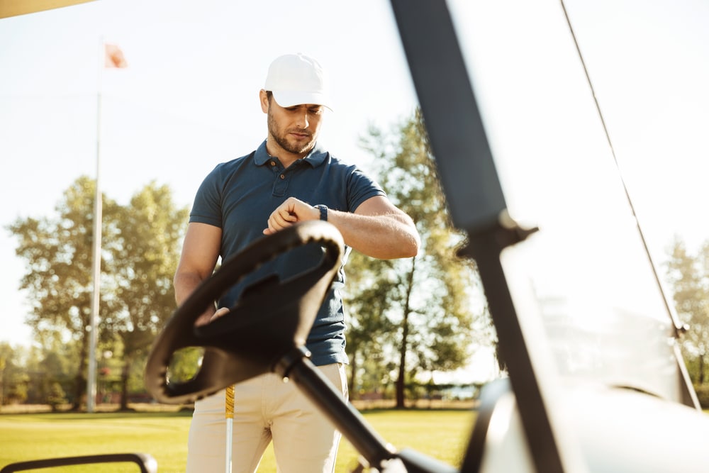 Young Male Golfer Looking At A Wristwatch While Standing At