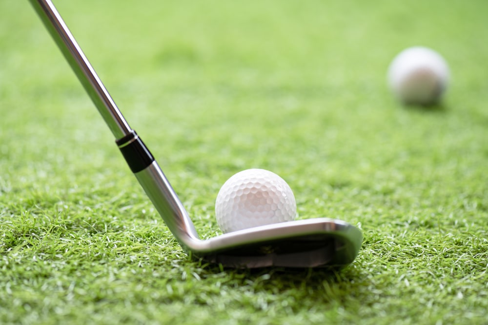 Selective Golf Club And Golf Ball On Green Grass Background iron